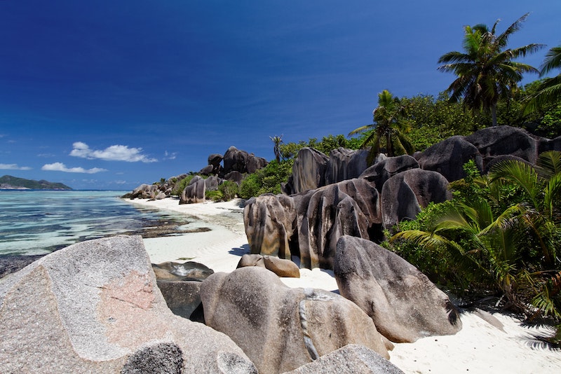 Beaches in Seychelles with white sand and typical cliffs, lined with nature with palm trees.