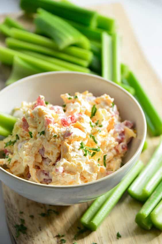 A bowl full of creamy spread with cheese and toasted bacon.