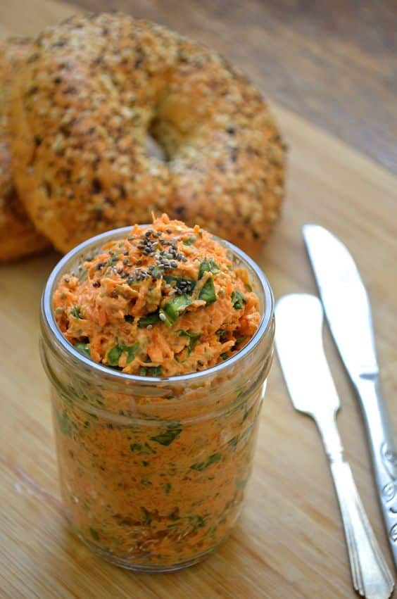 A jar full of cheese and carrot spread ready to be spread.