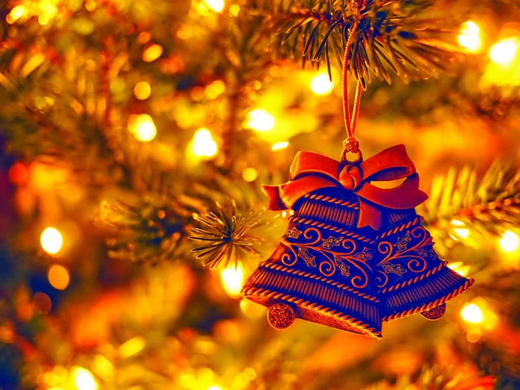 Detail of a glowing tree with a blue decoration in the shape of bells, connected by a red bow.