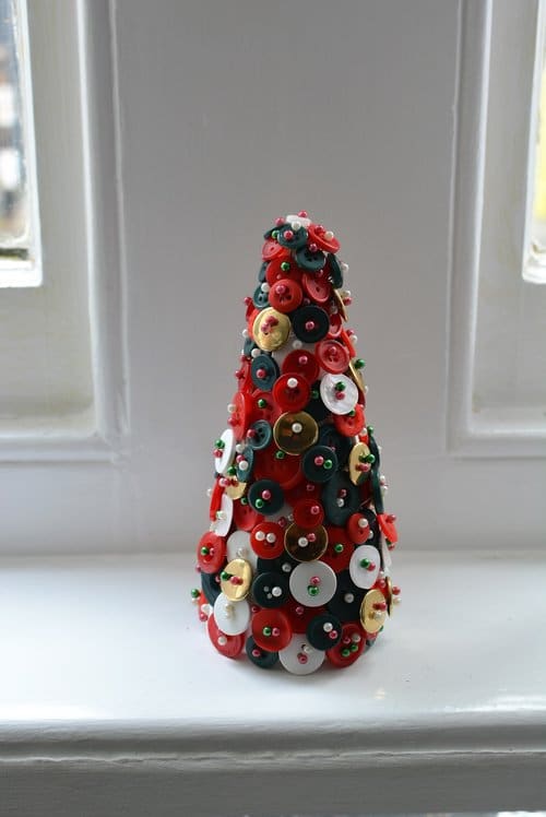 Christmas decoration of the apartment in the shape of a tree, made of colored buttons and pins.