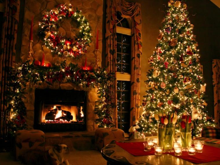 A room on a Christmas picture card with glowing decorations on a tree and above a burning fireplace.