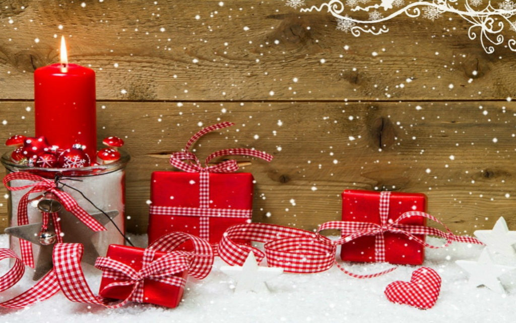 Postcard with red gifts and burning red candle in front of wooden background.