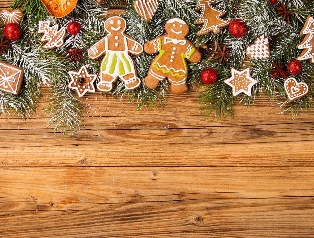 Wooden background decorated, in the upper part, with twigs, flasks and gingerbread with Christmas motifs.