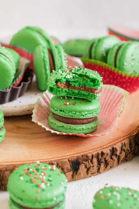 Green macaroons with Christmas sprinkles filled with creamy and rich dark chocolate filling.