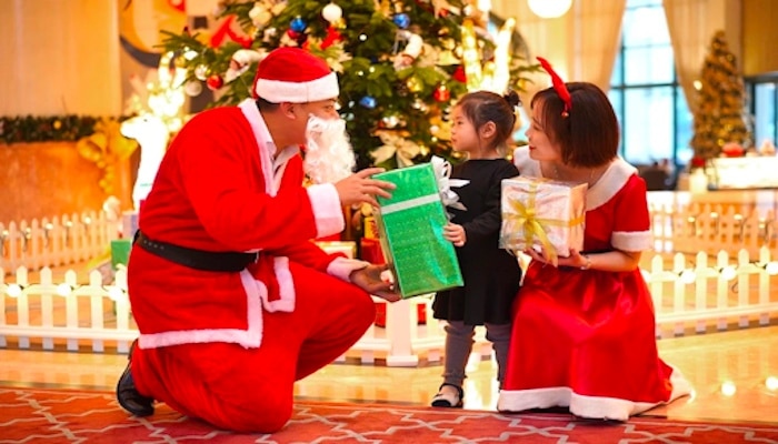 Vietnamese Santa Claus gives a gift to a small child.