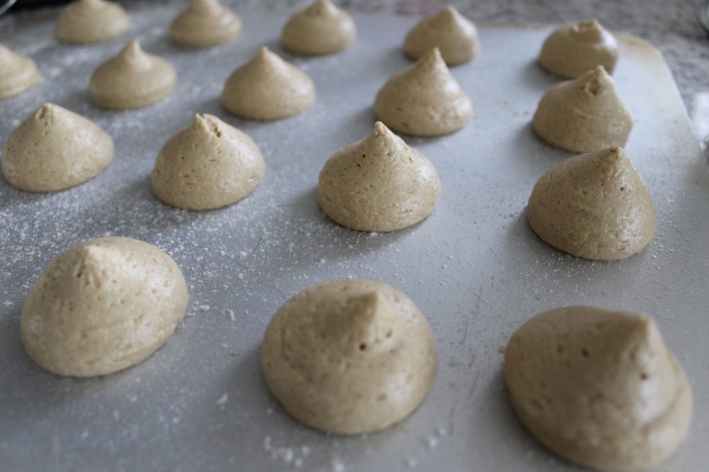 Nut meringues made of egg white stacked on a baking sheet.