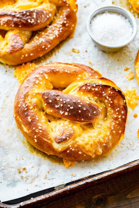 Stuffed pretzels on a baking sheet with dip.