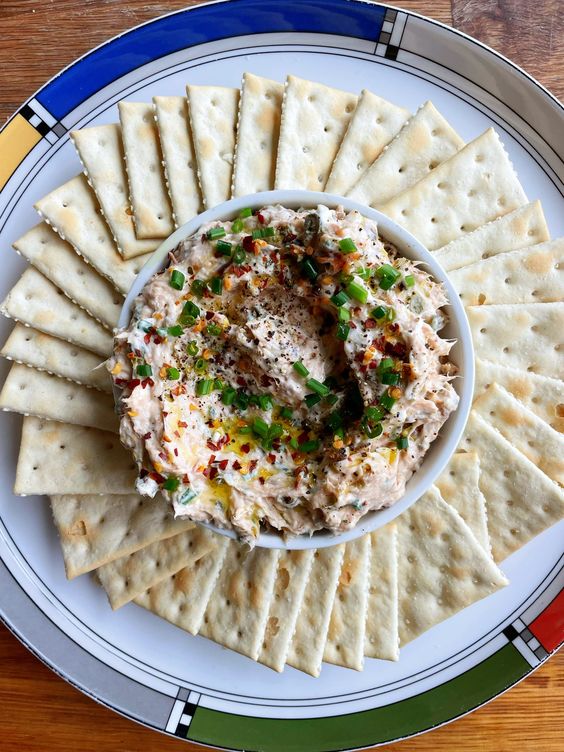 Spread with herbs, garlic and salami in a bowl with crackers.