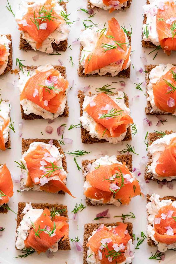 Pieces of whole wheat bread with pieces of smoked salmon and dill.