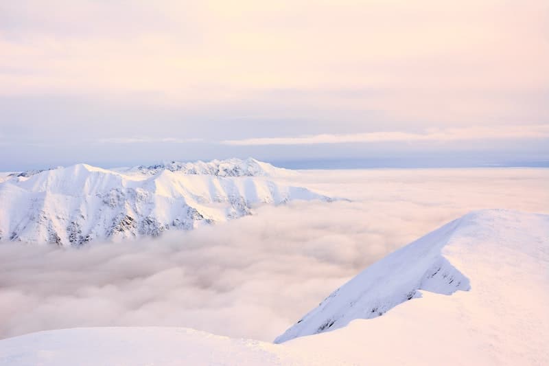 A view of the snowy high mountain massifs above the clouds.
