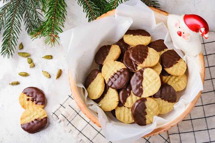 Christmas cookies dipped in chocolate coating in a bowl.