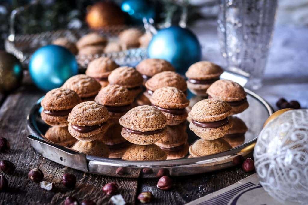 Christmas nuts made of rice flour and hazelnuts filled with hazelnut cream on a tray.