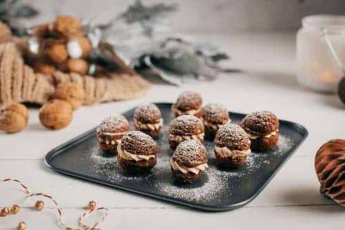 Nuts filled with vanilla pudding cream, milk chocolate and walnut paste on a baking sheet.