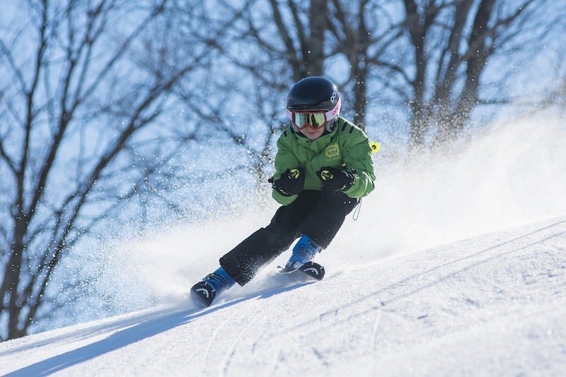 A boy skis wildly down a slope.