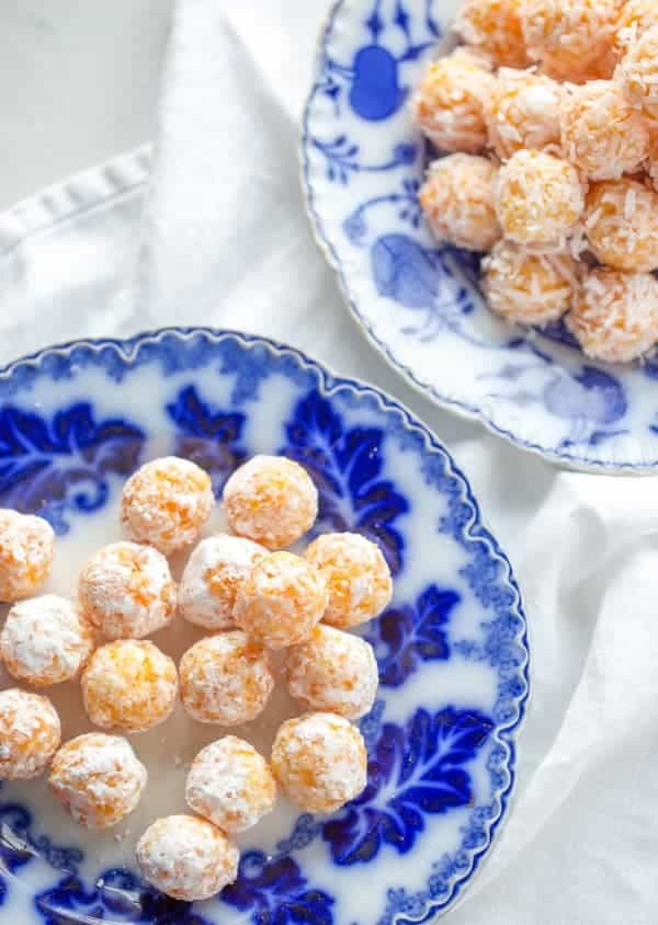 Coconut balls with apricots on plates.