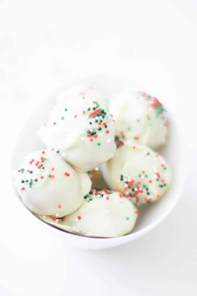 Nut balls in white chocolate with sprinkles in a bowl.