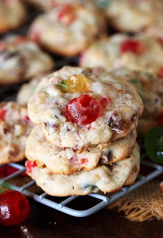 Christmas cookies filled with candied cherries, candied pineapple, pecans and dates stacked on top of each other.