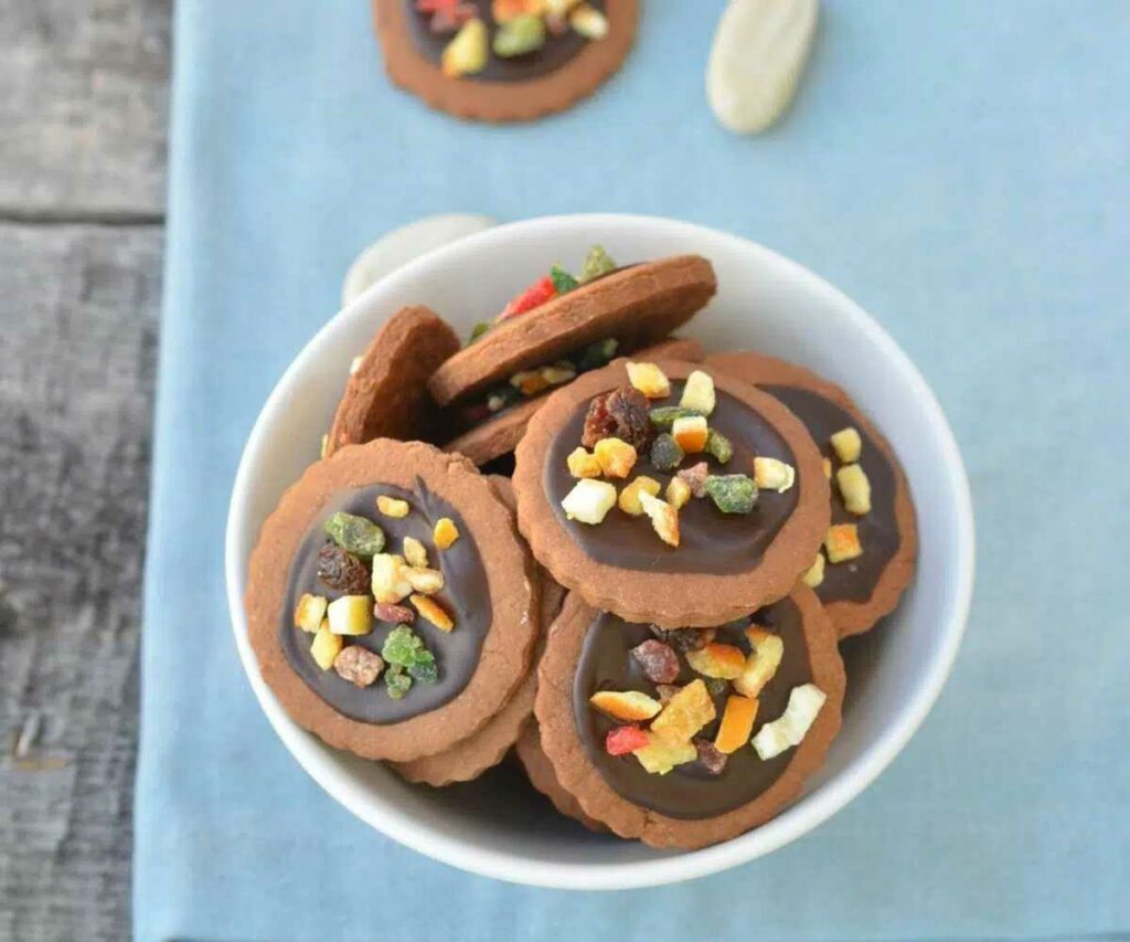 Cookies with chocolate and candied fruit in a bowl.