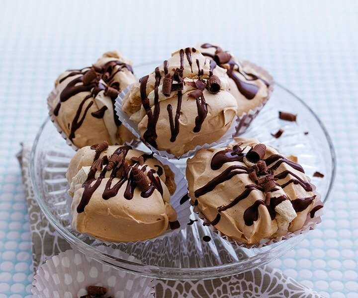 Cane sugar meringues filled with whipped cream with cinnamon and drizzled with melted chocolate on a serving tray.