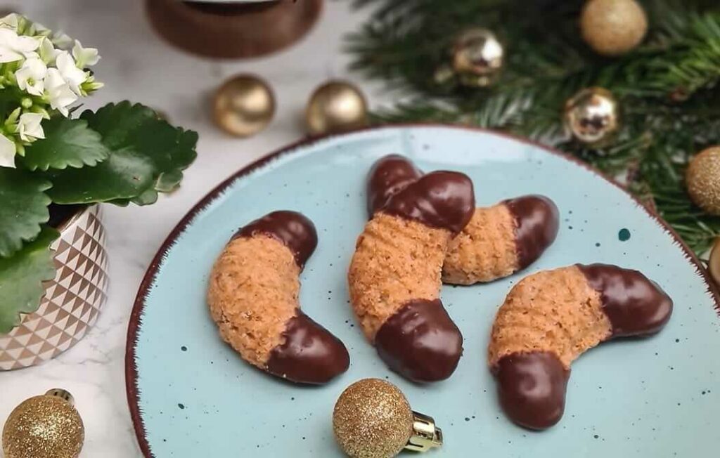 Nut rolls half-dipped in chocolate and served on a plate.