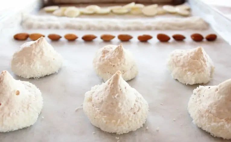 Meringues with homemade almond flour, dipped in white chocolate and covered in grated coconut.