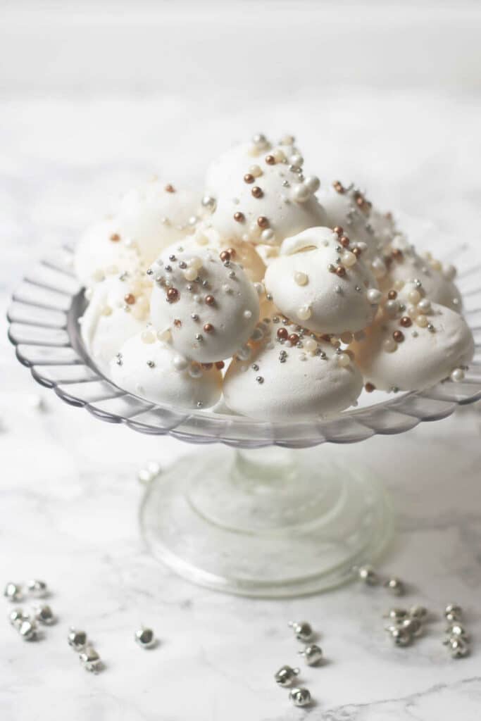 Snow meringues with coconut decorated with pearls and served on a serving tray.