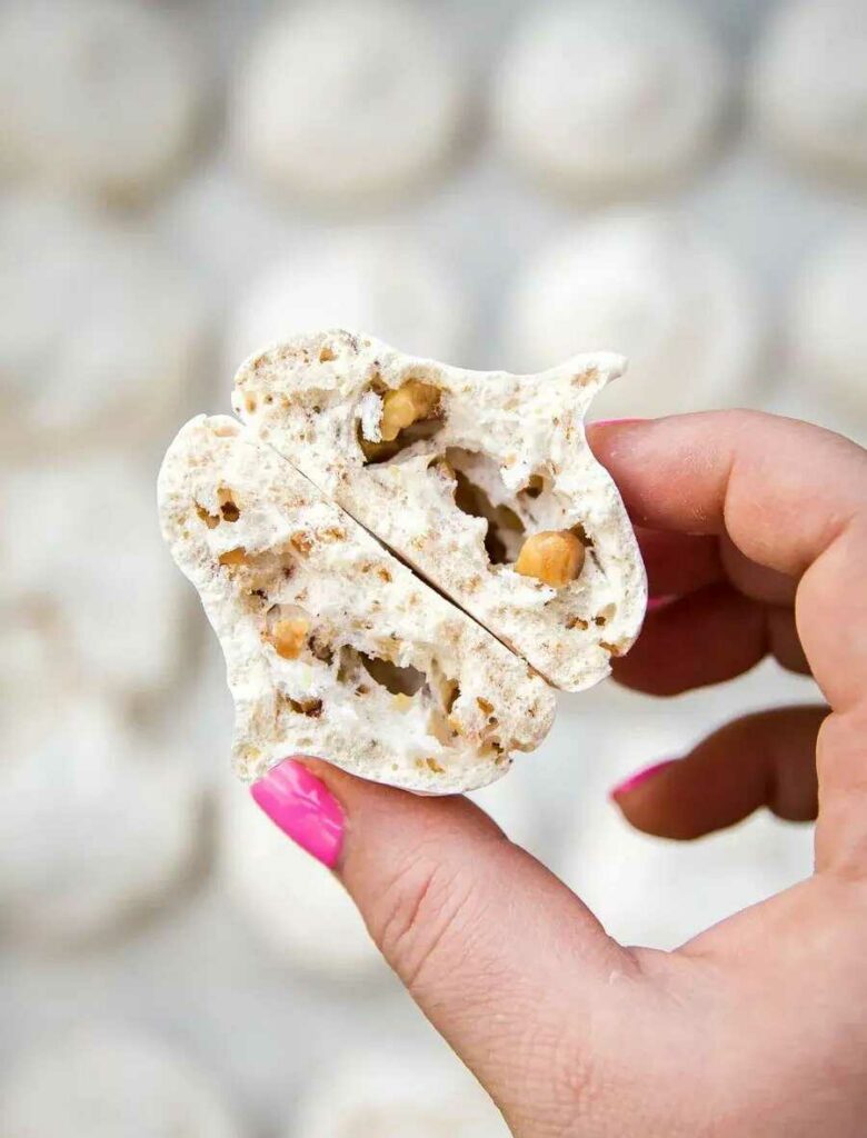 Two hazelnut meringues held by a hand.