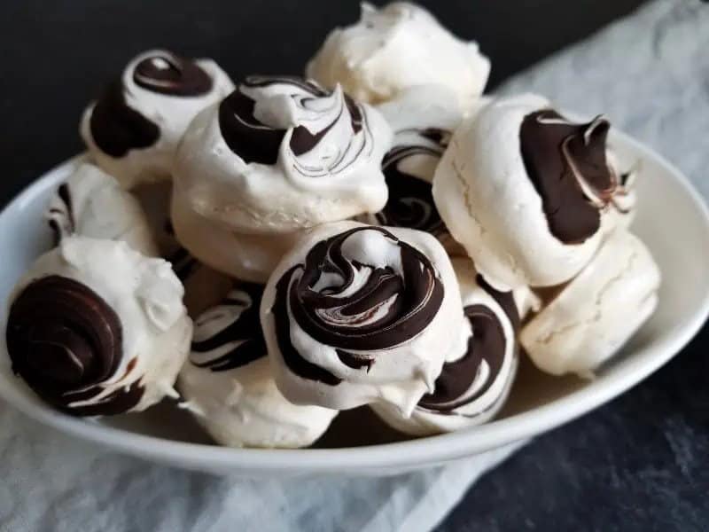 Meringue with chocolate swirls on a plate.