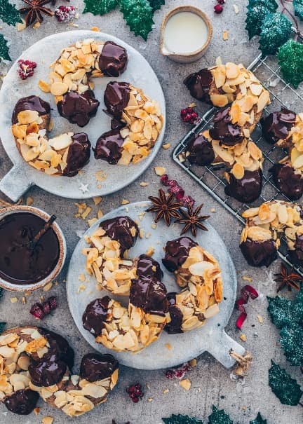 Christmas rolls sprinkled with sliced ​​almonds and dipped in chocolate served on plates.